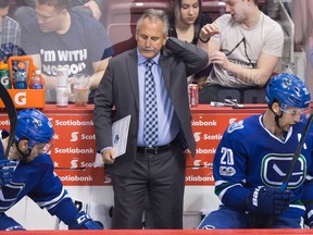 Vancouver Canucks head coach Willie Desjardins, centre, stands on the bench behind Michael Chaput, left, and Brandon Sutter during third period NHL hockey action against the Edmonton Oilers, in Vancouver, B.C., on Saturday, April 8, 2017.