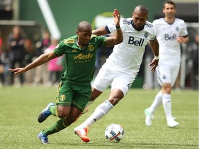 Portland Timbers' Darlington Nagbe, left, fights to get free before scoring a first-half goal during an MLS soccer game against the Vancouver Whitecaps, Saturday, April 22, 2017, in Portland, Ore.