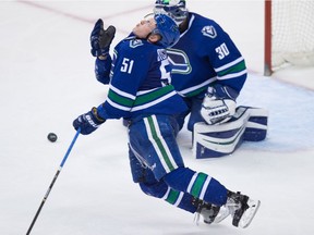 Vancouver Canucks' Troy Stecher takes a puck to the face during third period action against the Edmonton Oilers on Saturday.