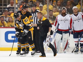 Sidney Crosby leaves the ice with trainer Chris Stewart after taking a hit in the first period against the Washington Capitals.