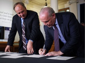 B.C. NDP Leader John Horgan, right, and B.C. Green party Leader Andrew Weaver sign an agreement on creating a stable minority government during a news conference in the Hall of Honour at the legislature in Victoria on May 30.