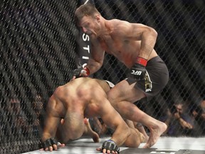 Stipe Miocic, top, knocks down Junior Dos Santos in their UFC heavyweight championship bout at UFC 211 in Dallas last week. Miocic retained his heavyweight title.