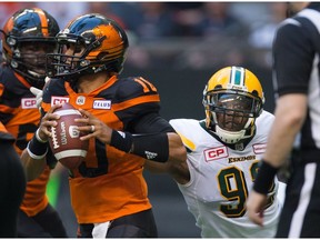 Edmonton Eskimos' Da'Quan Bowers, right, reaches to bring down B.C. Lions' quarterback Jonathon Jennings during the first half of Saturday's game at B.C. Place.