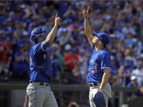 Toronto Blue Jays catcher Luke Maile, left, and closing pitcher Roberto Osuna point skyward together as they share congratulations after the team beat the Seattle Mariners in a baseball game Sunday in Seattle. The Blue Jays won 4-0.