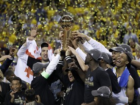 Golden State Warriors players, coaches and owners hold up the Larry O'Brien NBA Championship Trophy after Game 5 of basketball's NBA Finals between the Warriors and the Cleveland Cavaliers in Oakland, Calif., Monday, June 12, 2017. The Warriors won 129-120 to win the NBA championship. (AP Photo/Marcio Jose Sanchez) ORG XMIT: OAS177