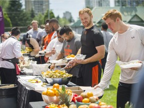 Travis Lulay #14 (black shirt) and the rest of the Lions grab lunch as Super Chefs prepare lunch for the BC Lions at the Lions practice facility in Surrey, B.C. on June 17, 2017.