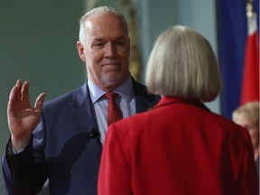 NDP Leader John Horgan takes an oath with Lieutenant-Governor Judith Guichon as he's sworn in as premier on Tuesday in Victoria.