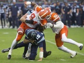 Toronto Argonauts quarterback Ricky Ray, centre, is sacked by BC Lions' DeQuin Evans, left, and Bryant Turner Jr. during first half CFL football action in Toronto on Friday.