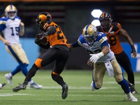 B.C. Lions' Ronnie Yell (25) is stopped by Winnipeg Blue Bombers' Andrew Harris after intercepting a pass from quarterback Matt Nichols, back left, during B.C.'s comeback win.