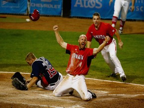 Peter Orr of Canada celebrates scoring the winning run in the 10th inning as Thomas Murphy of the USA and Tyler O'Neill of Canada looks after their Gold Medal match at the Pan Am Games on July 19, 2015 in Toronto. Canada won the game 7-6.