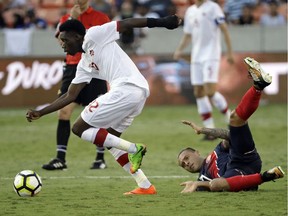 Costa Rica's David Ramirez, right, hits the ground after being tackled by Canada's Alphonso Davies, left, in the second half of a CONCACAF Gold Cup soccer match in Houston on Tuesday.