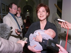 2001: Christy Clark, then deputy premier and minister of education, handles reporters’ questions while holding her one-month-old son Hamish at the B.C. legislature.