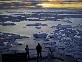 In this July 21, 2017 file photo, researchers look out from the Finnish icebreaker MSV Nordica as the sun sets over sea ice floating on the Victoria Strait along the Northwest Passage in the Canadian Arctic Archipelago. After 24 days at sea and a journey spanning more than 10,000 kilometers (6,214 miles), the Finnish icebreaker MSV Nordica has set a new record for the earliest transit of the fabled Northwest Passage. The once-forbidding route through the Arctic, linking the Pacific and the Atlantic oceans, has been opening up sooner and for a longer period each summer due to climate change. Sea ice that foiled famous explorers and blocked the passage to all but the hardiest ships has slowly been melting away in one of the most visible effects of man-made global warming.