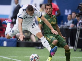 Vancouver Whitecaps defender Jake Nerwinski (28) fights for control of the ball with Portland Timbers midfielder Sebastian Blanco (10) during the first half of MLS soccer action in Vancouver on Sunday.