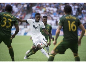 Alphonso Davies of the Vancouver Whitecaps tries to manoeuvre through a forest of Timbers' players during the second half of Sunday's MLS action in Vancouver. Portland won the match 2-1.