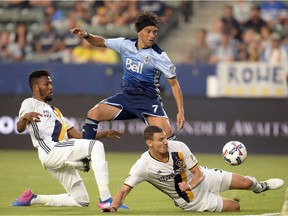 Los Angeles Galaxy defenders Bradley Diallo, left, and Daniel Steres work to check Vancouver Whitecaps midfielder Christian Bolanos during the first half of Wednesday's Major League Soccer match at StubHub Center in Carison, Calif.