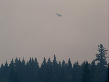 A helicopter carrying a bucket battles the Gustafsen wildfire near 100 Mile House, B.C., on Saturday July 8, 2017.