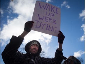 Dean Anderson holds up a sign before a march on the first National Day of Action to draw attention to the opioid overdose epidemic, in the Downtown Eastside of Vancouver on Feb. 21, 2017.