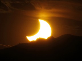 FILE - In this May 20, 2012, file photo, the annular solar eclipse is seen as the sun sets behind the Rocky Mountains from downtown Denver. The solar eclipse that is cutting a diagonal path across the U.S. next month is a boon for Missouri tourism. Some towns will have more visitors than residents on Aug. 21, 2017. Hotels and campsites are sold out as some communities are preparing for unparalleled numbers of visitors, all to observe about two minutes of near-darkness at the height of the day. (AP Photo/David Zalubowski, File) ORG XMIT: CER803