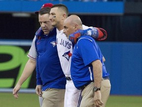 Toronto Blue Jays&#039; Troy Tulowitzki, centre, is helped off the field by trainers Mike Frostad, left, and George Poulis after he injured himself awkwardly running across the first base bag in the third inning of their American League MLB baseball game against the Los Angeles Angels in Toronto on Friday, July 28, 2017. Troy Tulowitzki still hasn&#039;t watched the replay footage of him rolling his ankle a month ago.He doesn&#039;t want to. Nor does he need to. THE CANADIAN PRESS/Fred Thornhill