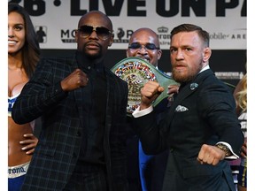 Boxer Floyd Mayweather Jr., left, and UFC lightweight champion Conor McGregor pose as Mayweather Promotions CEO Leonard Ellerbe (C) looks on during a Wednesday news conference n Las Vegas, Nevada. Mayweather and McGregor will meet in a super welterweight boxing match at T-Mobile Arena on Saturday in Las Vegas.