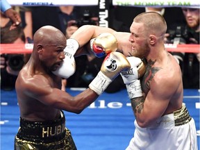 Floyd Mayweather (L) and Jr. Conor McGregor battle in the sixth round of their super welterweight boxing match Saturday in Las Vegas. Mayweather won by 10th-round TKO.