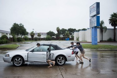 People push a disabled car during the aftermath of Hurricane Harvey August 27, 2017 in Houston, Texas. Hurricane Harvey left a trail of devastation Saturday after the most powerful storm to hit the US mainland in over a decade slammed into Texas, destroying homes, severing power supplies and forcing tens of thousands of residents to flee.