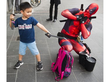 A young boy strikes a pose with Taylor Hoffmann's Deadpool swords outside the Anime Revolution Summer convention at Canada Place.