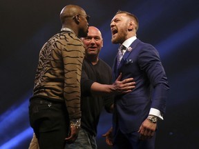 Boxers Connor McGregor, right and Floyd Mayweather left, are separated by UFC President Dana White, during a press conference to promote their upcoming fight, at the SSE Arena, in Wembley, London in earlu July.