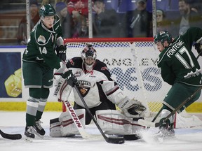 Ryan Kubic of the Vancouver Giants makes a save against Riley Sutter and Matt Fonteyne of the Everett Silvertips during the third period of their WHL game at the Langley Events Centre on Dec. 27, 2016.