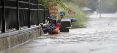 Residents wade through floodwaters from Tropical Storm Harvey Sunday, Aug. 27, 2017, in Houston, Texas.