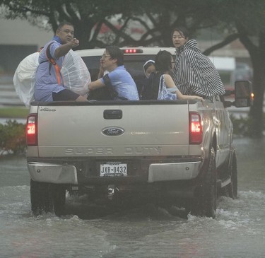 People get a ride from a passerby as they evacuate floodwaters from Tropical Storm Harvey on Sunday, Aug. 27, 2017, in Houston, Texas.