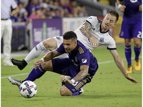 Dom Dwyer of the Orlando City FC Lions, front, gets tangled up with Jordan Harvey of the Vancouver Whitecaps while going for the ball during Saturday's Major League match in Florida. The Whitecaps won 2-1.