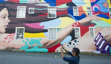 A man photographs a mural by David Ullock and Douglas Nhung at the Vancouver Mural Festival held in Mount Pleasant, Vancouver.