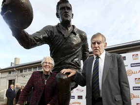 In this June 19, 2017 file photo, former All Black great, Sir Colin Meads, right, and his wife Vera pose for a photo with the statue of himself at the unveiling in Te Kuiti, New Zealand.