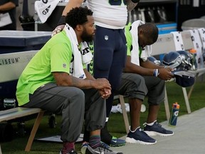 FILE - This Thursday, Aug. 31, 2017 file photo Seattle Seahawks defensive end Michael Bennett, left, sits during the playing of the national anthem next to Justin Britt, center, and another teammate before an NFL preseason football game between the Raiders and the Seattle Seahawks in Oakland, Calif. Bennett is accusing Las Vegas police of racially motivated excessive force when he says he was detained at gunpoint on Aug. 27, 2017, handcuffed and later released without charges following a report