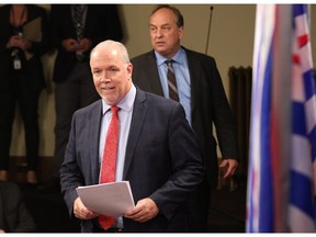 Premier John Horgan, left, and Green party Leader Andrew Weaver speak to media Monday in Victoria after the minority NDP government introduced legislation banning union and corporate donations to political parties and introducing taxpayer subsidies instead.