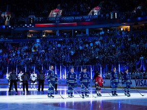 Vancouver Canucks and San Jose Sharks players stand during the singing of the national anthems last season.