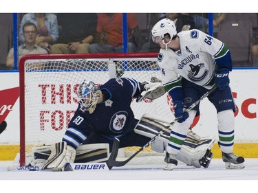 Winnipeg Jets goalie Mikhail Berdin (left) makes a pad save with Vancouver Canucks Zack MacEwen.