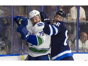 Winnipeg Jets Mathieu Sevigny (right) hits Vancouver Canucks Danny Moynihan along the end boards.