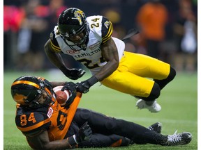 Demond Washington of the Hamilton Tiger-Cats falls on B.C. Lions' Emmanuel Arceneaux during Friday's CFL game at B.C. Place Stadium in Vancouver. The Tiger-Cats finished on top, too, with a 24-23 victory.