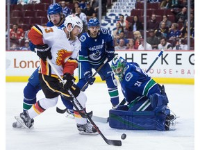 Netminder Anders Nilsson of the Vancouver Canucks makes a save against Calgary Flames' Sam Bennett, while Vancouver's Andrey Pedan, back left, and Chris Tanev look on during Thursday's NHL pre-season game at Rogers Arena in Vancouver.