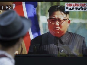 A man watches a TV news program on a public screen showing an image of North Korean leader Kim Jong Un.