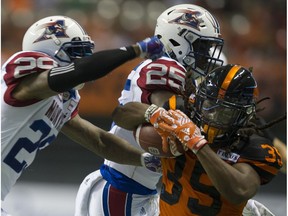 Shaquille Murray-Lawrence of the B.C. Lions is pushed out of bounds by Montreal Alouettes Jonathon Mincy, left, and Dondre Wright during Friday's CFL game at B.C. Place Stadium in Vancouver.