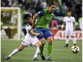 Christian Bolanos of the Vancouver Whitecaps, left, guards Seattle Sounders' Gustav Svensson during Wednesday's MLS match in Seattle. The Caps were clobbered 3-0 at CenturyLink Field.