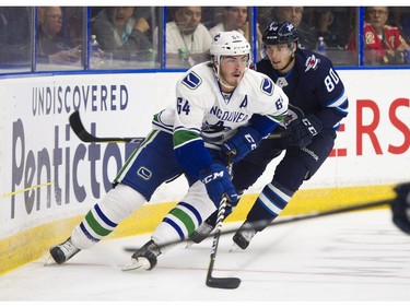 Vancouver Canucks Zack MacEwen (64) beats Winnipeg Jets Michael Spacek (80) to the loose puck.