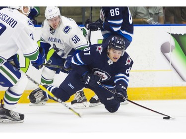 Winnipeg Jets Cristiano DiGiacinto (87) tries to maintain control of the puck after getting tripped up by Vancouver Canucks Michael Carcone (58).