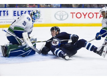 Winnipeg Jets Mason Appleton (right) crashes into Vancouver Canucks goalie Thatcher Demko after losing an edge and the puck.