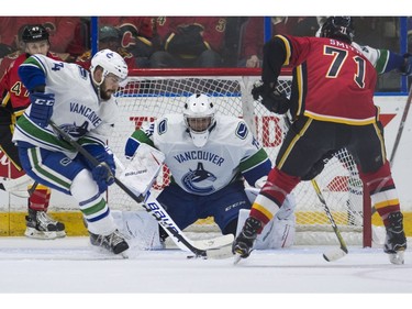 Vancouver Canucks goalie Michael DiPietro (middle) keeps an watches Canucks Yan-Pavel Laplante (left) clear the puck while pressured by Calgary Flames Hunter Smith.