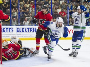 Vancouver Canucks Yan-Pavel Laplante (centre) celebrates after scoring a goal against Calgary Flames goalie Nick Schneider (left) during NHL preseason hockey action at the Young Stars Classic held at the South Okanagan Events Centre in Penticton, BC, September, 10, 2017.